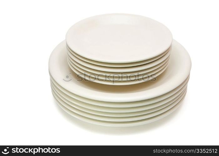 Stack of plain beige dinner plates and saucers isolated