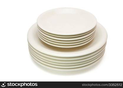 Stack of plain beige dinner plates and saucers isolated