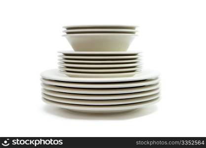 Stack of plain beige dinner plates, soup plates and saucers isolated