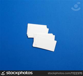 stack of rectangular white blank business cards on a blue background. Corporate business concept