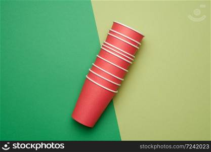 stack of red paper disposable cups on a green background, flat lay, concept eco-friendly, zero waste