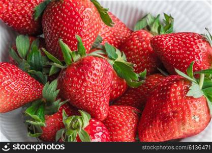 Stack of red strawberries in a white cup