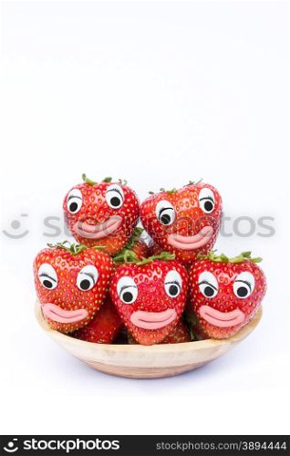 stack of red strawberries on wooden scale. Fruit with eyes and mouths isolated on white background