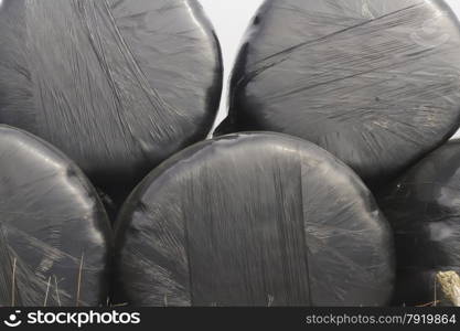 Stack of silage bales, wrapped in black plastic, on small bank.