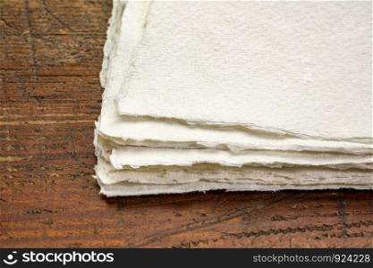 stack of small sheet of blank white Khadi rag paper from South India against rustic wood