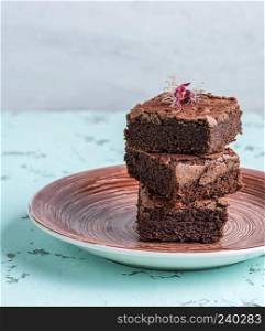 stack of square pieces of baked brownies on a round ceramic plate