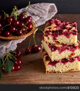 stack of square slices of a baked pie with cherry berries on a brown wooden board