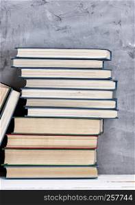 stack of various books on the table, gray background, copy space