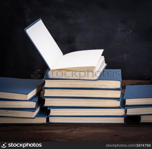 stack of various books, open book on top, close up
