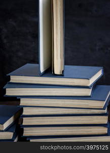 stack of various books, open book on top, close up