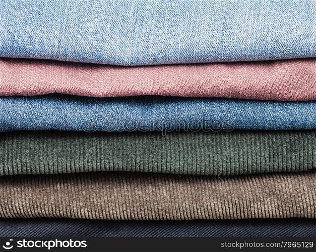 stack of various jeans and corduroy slacks close up