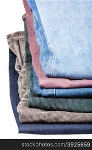 stack of various jeans and corduroys close up isolated on white background