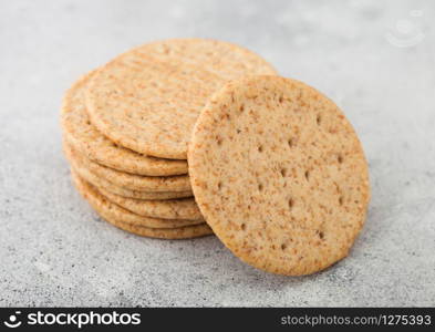 Stack of various organic crispy wheat crackers with sesame and salt on light background.