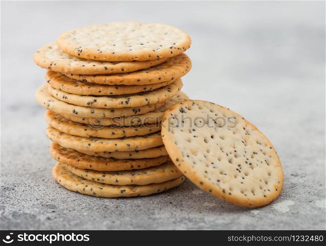 Stack of various organic crispy wheat flatbread crackers with sesame and salt on light background.