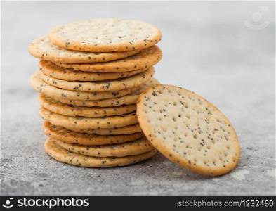 Stack of various organic crispy wheat flatbread crackers with sesame and salt on light background.
