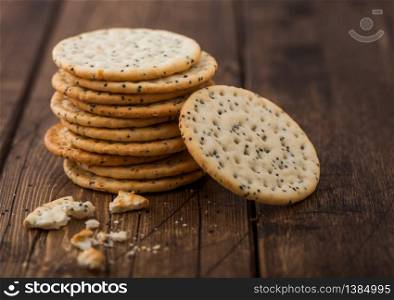 Stack of various organic crispy wheat flatbread crackers with sesame and salt on wood background.