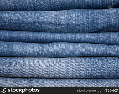 stack of various shades of jeans as background. stack of various shades of blue jeans as background