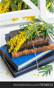 stack of vintage old books with yellow mimosa flowers. pile of old books