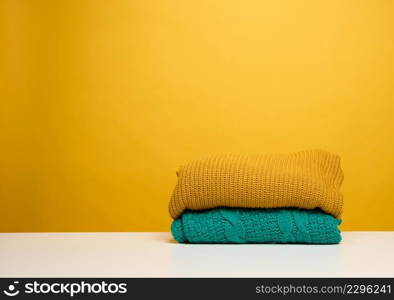 stack of washed folded clothes on a white table, yellow background. Routine homework, copy space
