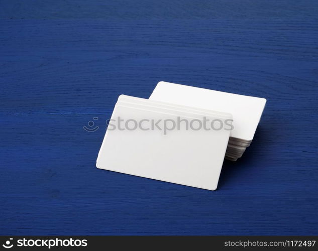 stack of white blank paper rectangular business cards on blue wooden background, template for designer