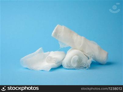 stack of white medical gauze cotton bandages on a blue background, close up
