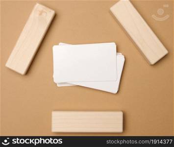 stack of white rectangular business cards on a brown background, company branding, address. View from above, flat lay