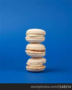 stack of white round baked almond flour cakes macarons on a dark blue background, delicious popular french dessert, close up
