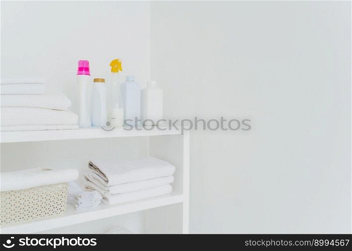 Stack of white soft towels with soft conditioner liquid. White background with copy space for your information. Cleanliness concept. Natural light