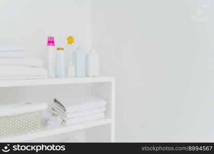 Stack of white soft towels with soft conditioner liquid. White background with copy space for your information. Cleanliness concept. Natural light