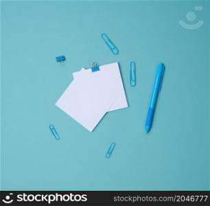 stack of white square sheets of paper for notes, stationery on blue background, top view