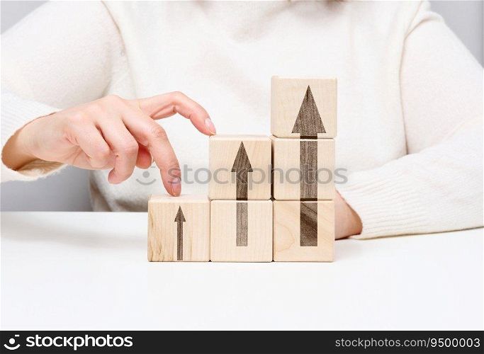 Stack of wooden cubes, the person’s fingers go up the steps. Business growth concept, goal achievement, self-education, career success