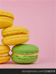 stack of yellow and green round almond flour cakes macarons with cream on a pink background, delicious cake