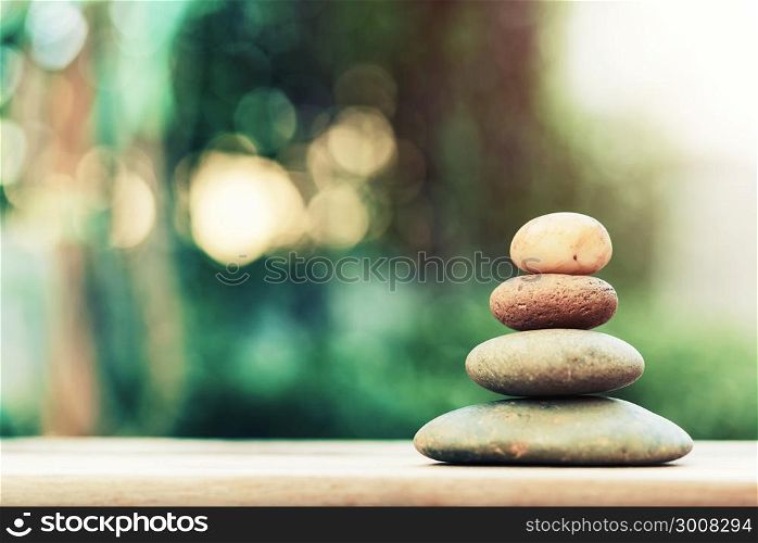 Stack of zen stones on ground with blurred nature background.