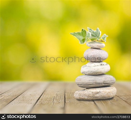 Stack pebbles on wooden table with green background