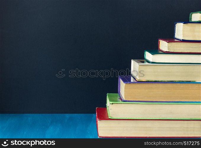 Stack steps stairs of old books on background black chalkboard, copy space, concept education, way road to knowledge. Stack steps stairs of old books on background black chalkboard