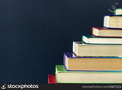 Stack steps stairs of old books on background black chalkboard, copy space, concept education, way road to knowledge. Stack steps stairs of old books on background black chalkboard