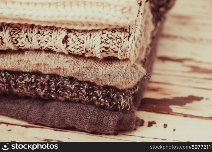 Stack warm knitted sweaters in white and gray shades. Collection of woolen clothes