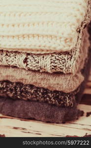 Stack warm knitted sweaters in white and gray shades. Collection of woolen clothes