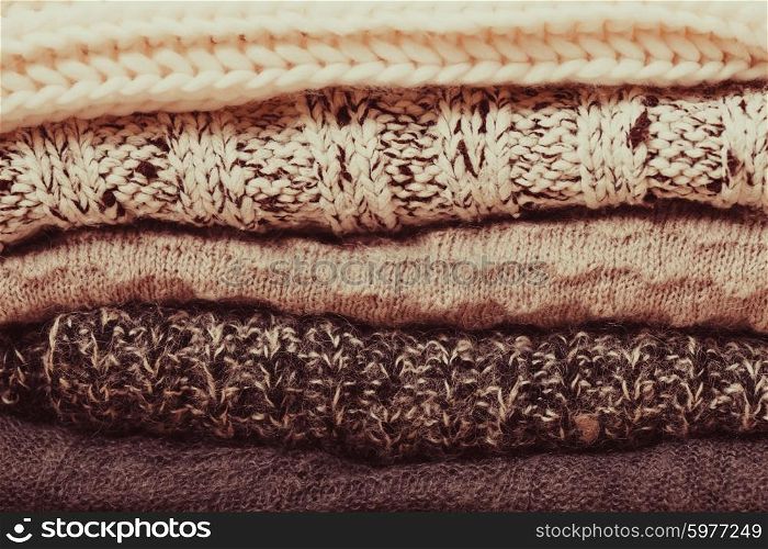 Stack warm knitted sweaters in white and gray shades. Collection of woolen clothes