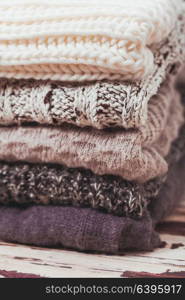 Stack warm knitted sweaters in white and gray shades. Collection of woolen clothes