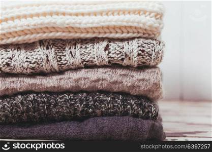 Stack warm knitted sweaters in white and gray shades. Collection of woolen clothes