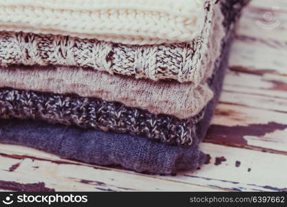 Stack warm knitted sweaters in white and gray shades. Collection of woolen clothes