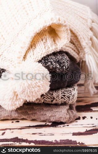 Stack warm knitted sweaters, scarf and hat in white and gray shades