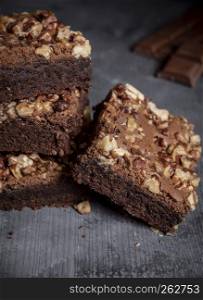 Stack with sweet brownies cake decorated with walnuts on a rustic wooden table