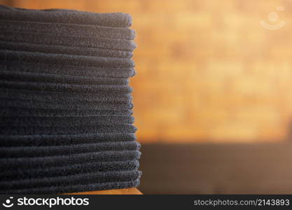 stacked black bathroom towels on a wooden table and brick wall background. spa salon, barbershop. stacked black bathroom towels on a wooden table and brick wall background. spa salon, barbershop.