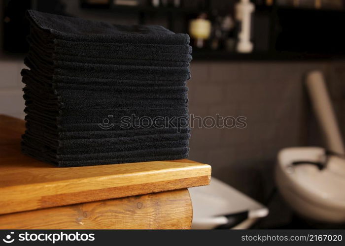 stacked black bathroom towels on a wooden table and brick wall background. spa salon, barbershop. stacked black bathroom towels on a wooden table and brick wall background. spa salon, barbershop.