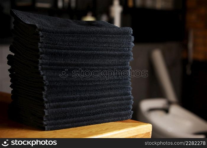 stacked black bathroom towels on a wooden table and brick wall background. spa salon, barbershop. stacked black bathroom towels on a wooden table and brick wall background. spa salon, barbershop.