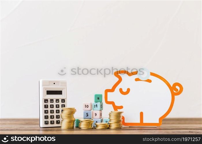 stacked coins math blocks calculator piggybank wooden tabletop. High resolution photo. stacked coins math blocks calculator piggybank wooden tabletop. High quality photo
