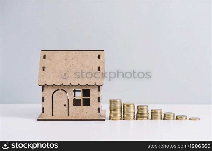 stacked coins near house model against white background. High resolution photo. stacked coins near house model against white background. High quality photo