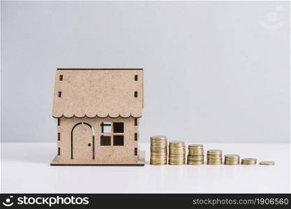 stacked coins near house model against white background. High resolution photo. stacked coins near house model against white background. High quality photo